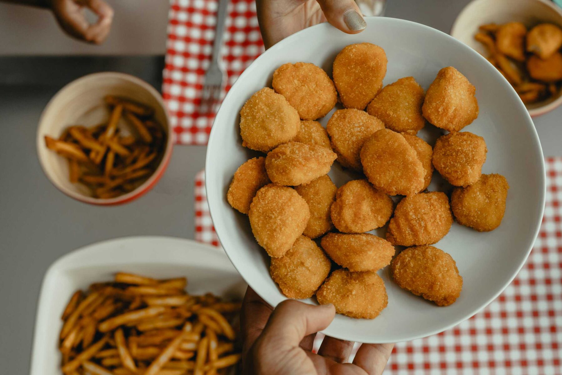 Plate of chicken nuggets with plain fries in the background