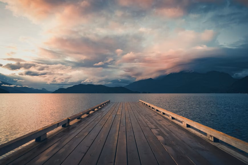 View of the end of a dock looking out over water and mountains
