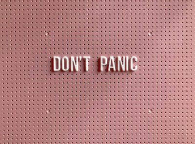Pink board with the words "DON'T PANIC" stuck on in white