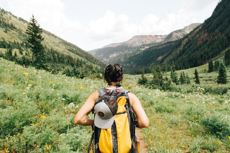 Woman with a yellow backpack hiking through hills